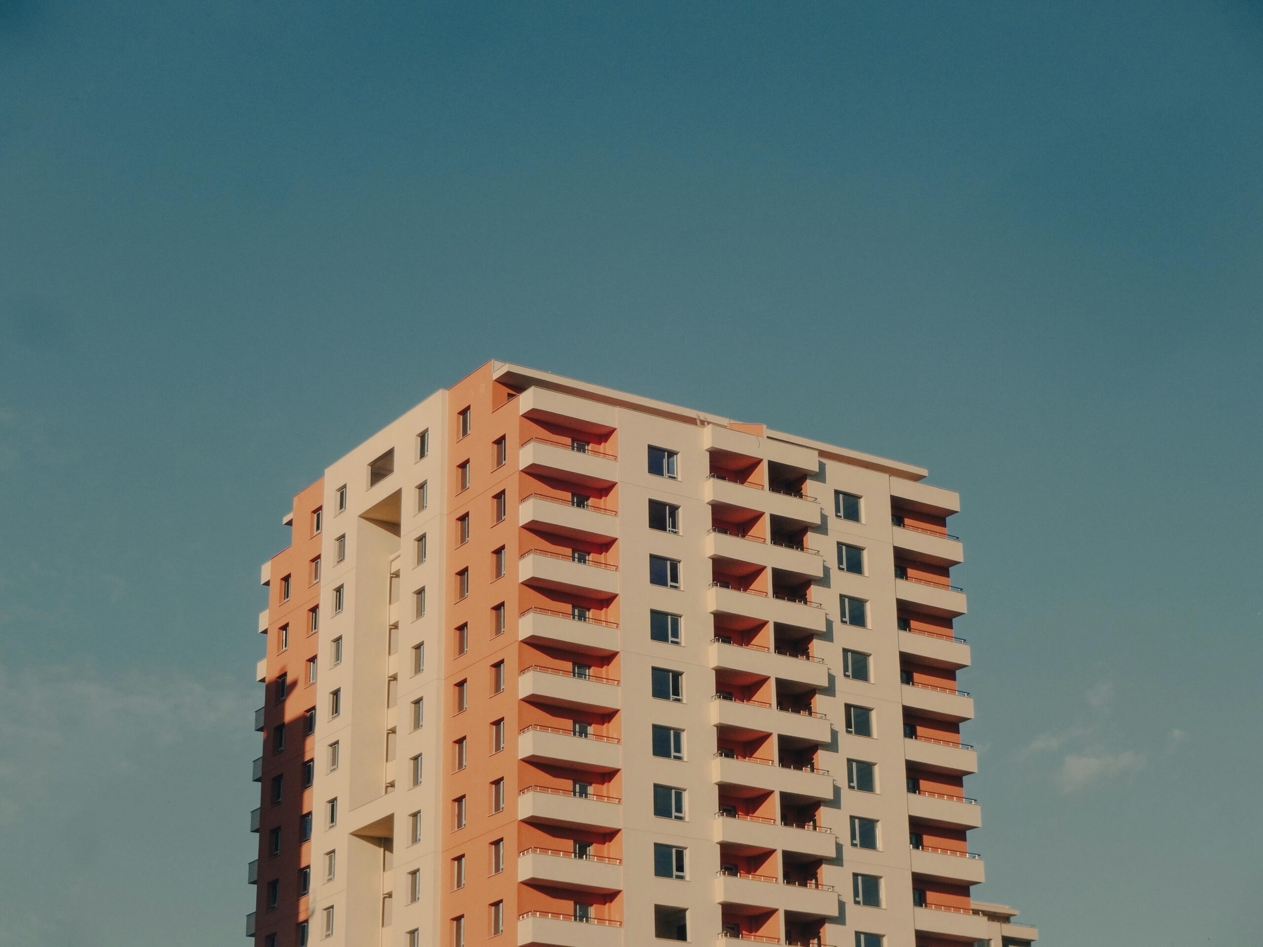 A modern high-rise building with a colorful facade against a clear blue sky.